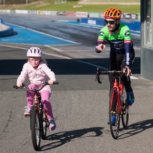 Young girl on bicycle with pro rider